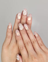 Hand wearing Naillover Pearl Bloom Bronze handmade press on nails with floral bronze design, shimmering accents, and rhinestone details.